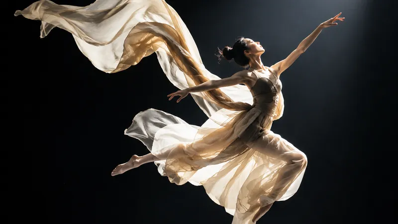 Performer mid leap with flowing fabric under a hard spotlight
